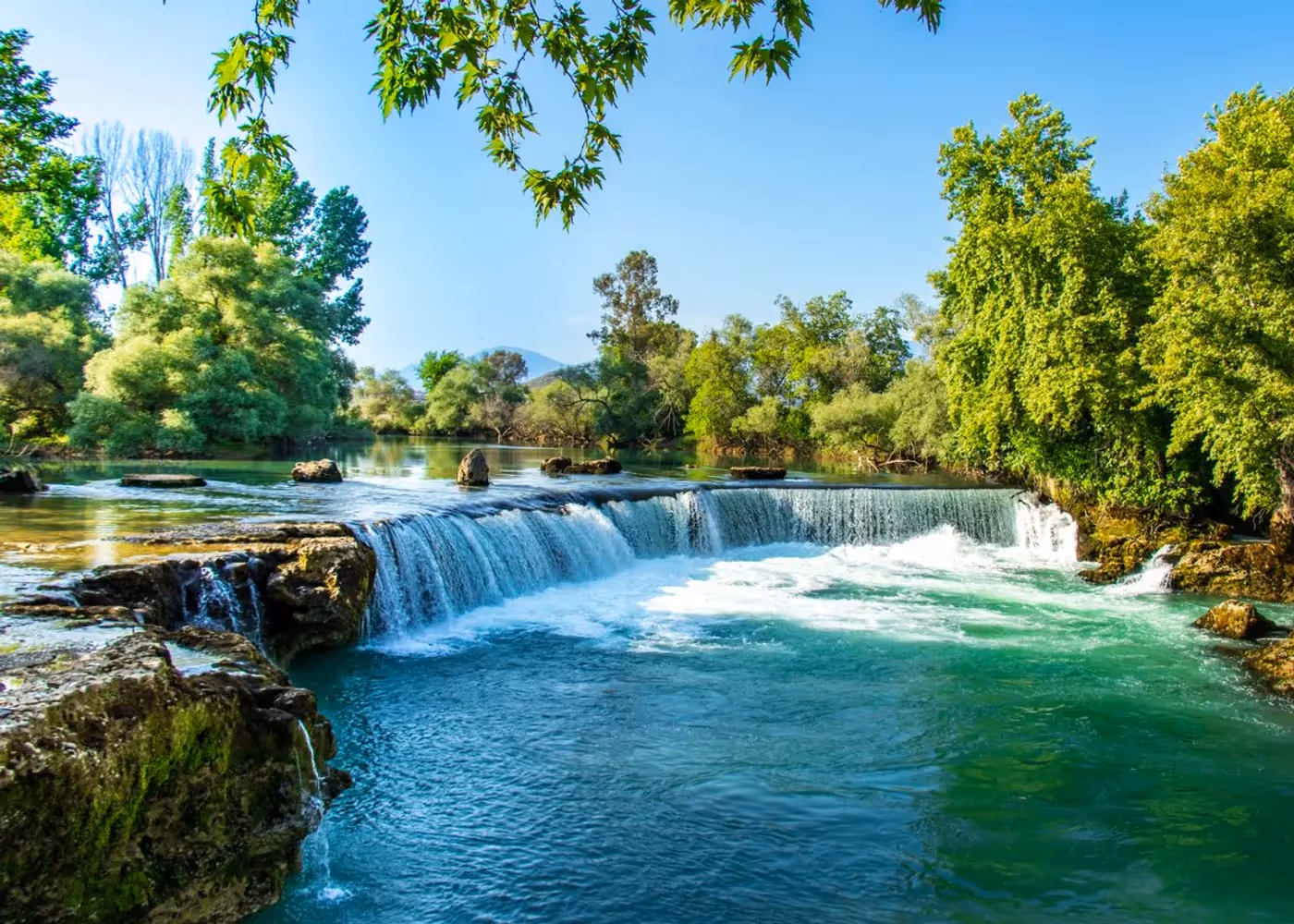 Het water van de Manavgat-rivier stroomt over een brede, lage rotsrand