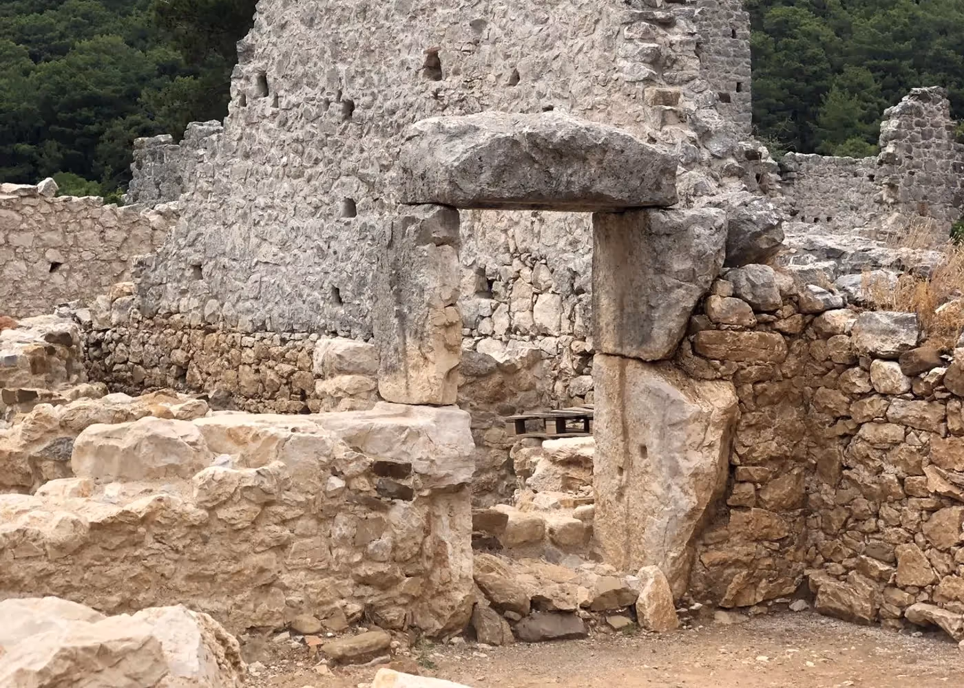 Overwoekerde stenen muur van een gebouw in de antieke stad Olympos