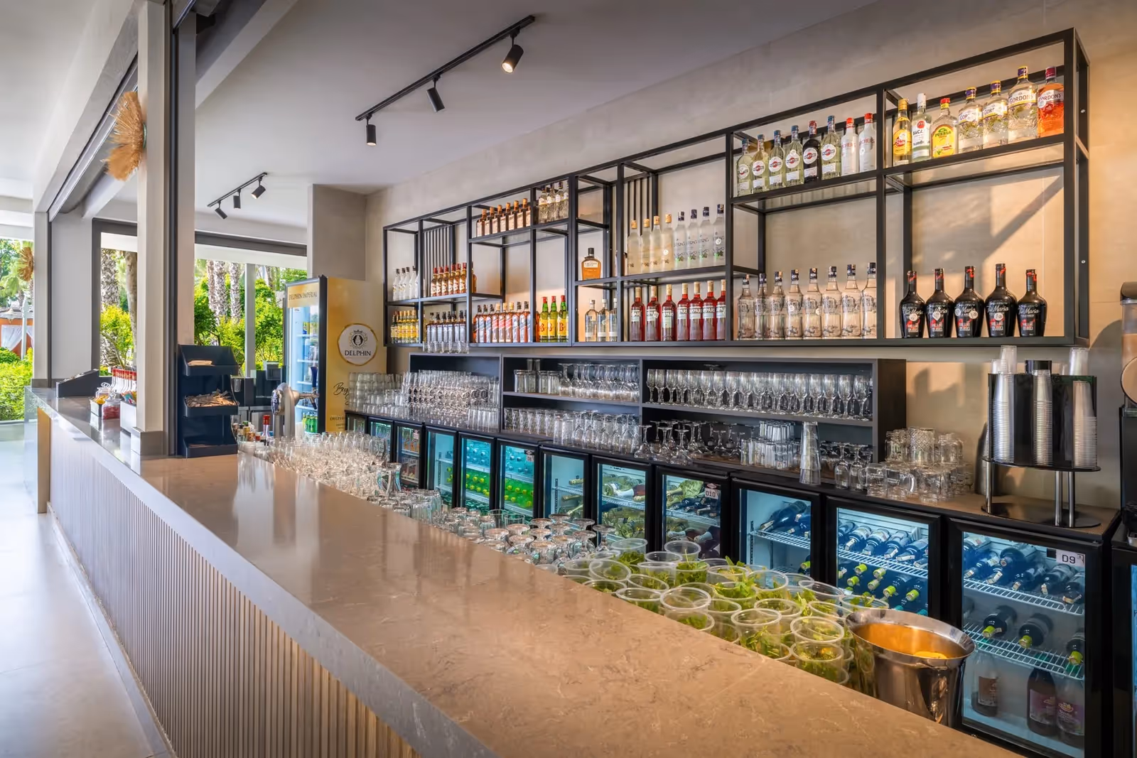 Bar met een lange toog, flessen en wijnkoelkasten bij Delphin Imperial in Lara