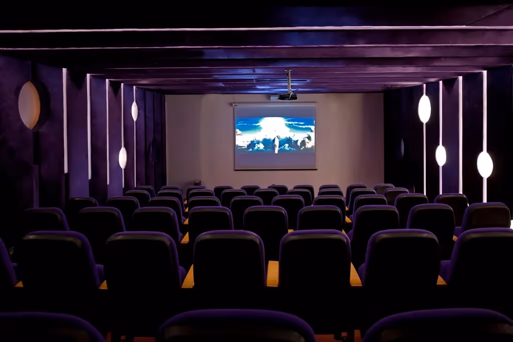 Bioscoopzaal van Delphin Imperial met rijen paarse stoelen en een projectiescherm