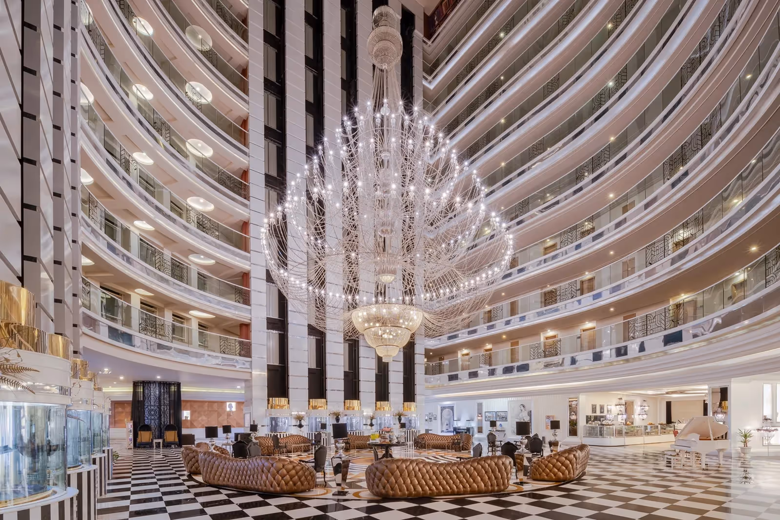 Lobby met een atrium over alle verdiepingen, een grote kroonluchter en een zwart-witte vloer in Delphin Imperial in Lara