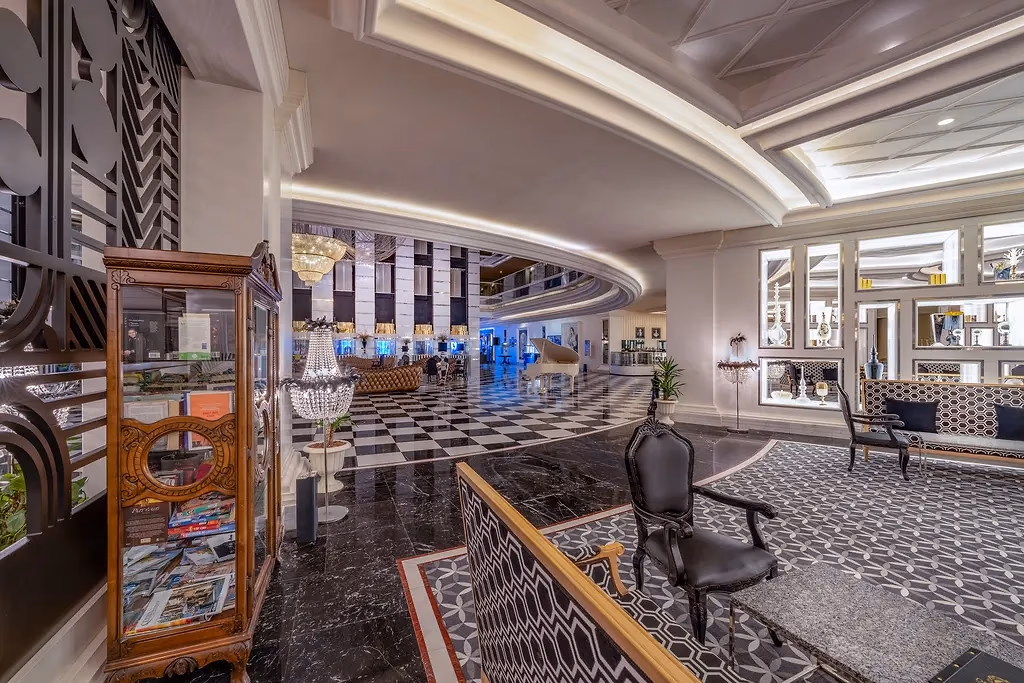 De lobby van Delphin Imperial met een zwart-wit geblokte vloer, kroonluchters en zithoeken