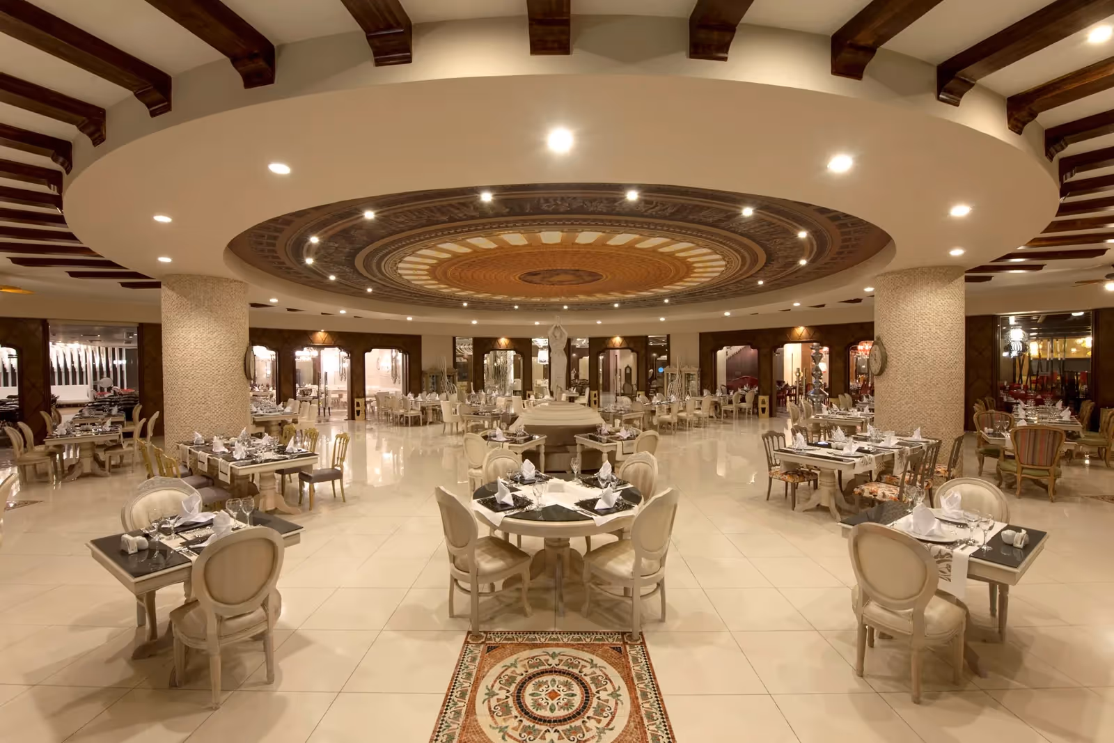 Restaurantzaal met gedekte tafels, lichte stoelen en een rond verlaagd plafond met spots in Delphin Imperial in Lara