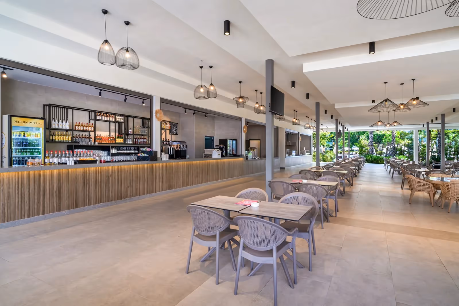 Open restaurant met bar, tafels en stoelen en doorkijk naar de tuin bij Delphin Imperial in Lara