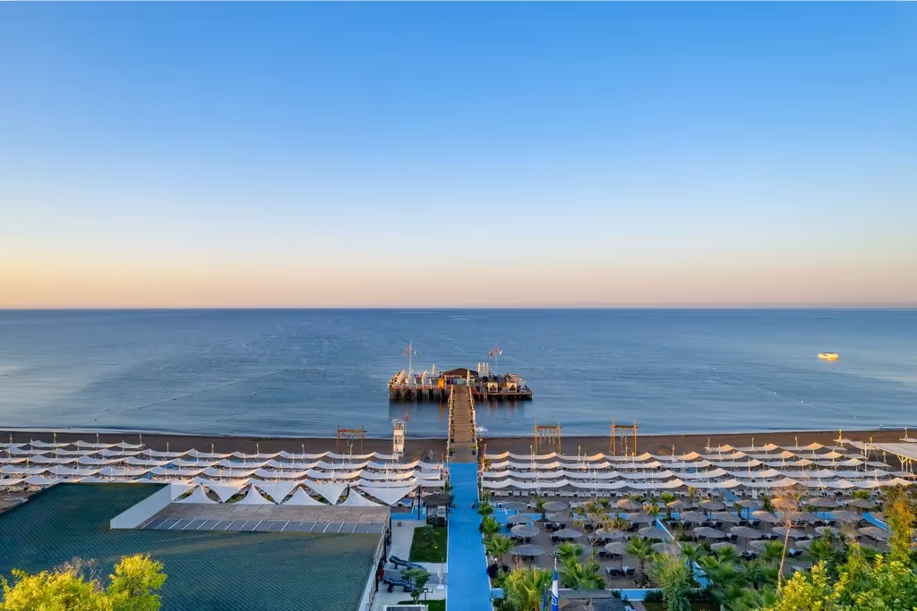 De steiger van Delphin Imperial in Lara met rijen ligbedden en parasols op het strand ervoor