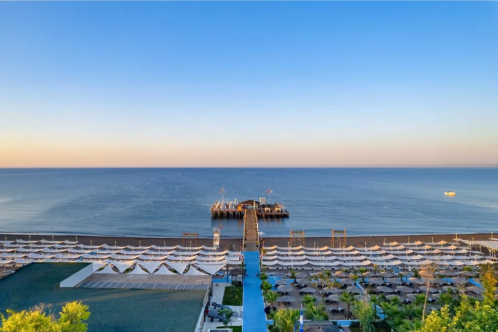 De steiger van Delphin Imperial in Lara met rijen ligbedden en parasols op het strand ervoor