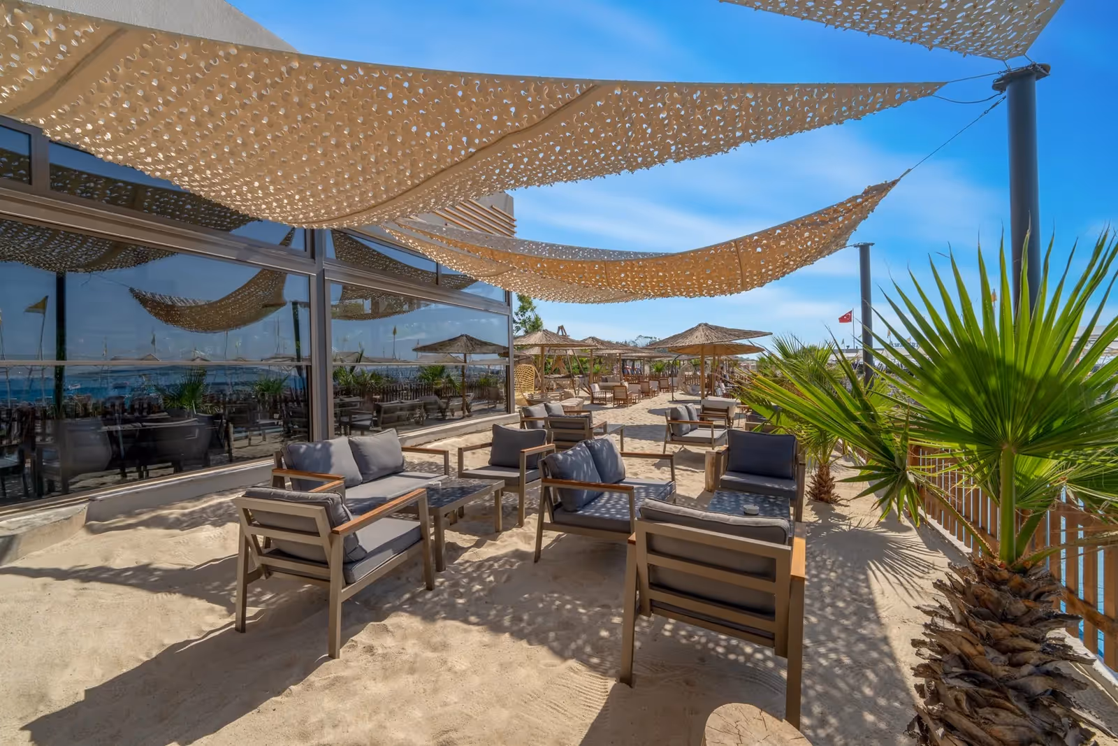 Terras op het zand met loungestoelen onder schaduwdoeken en uitzicht op zee bij Delphin Imperial in Lara
